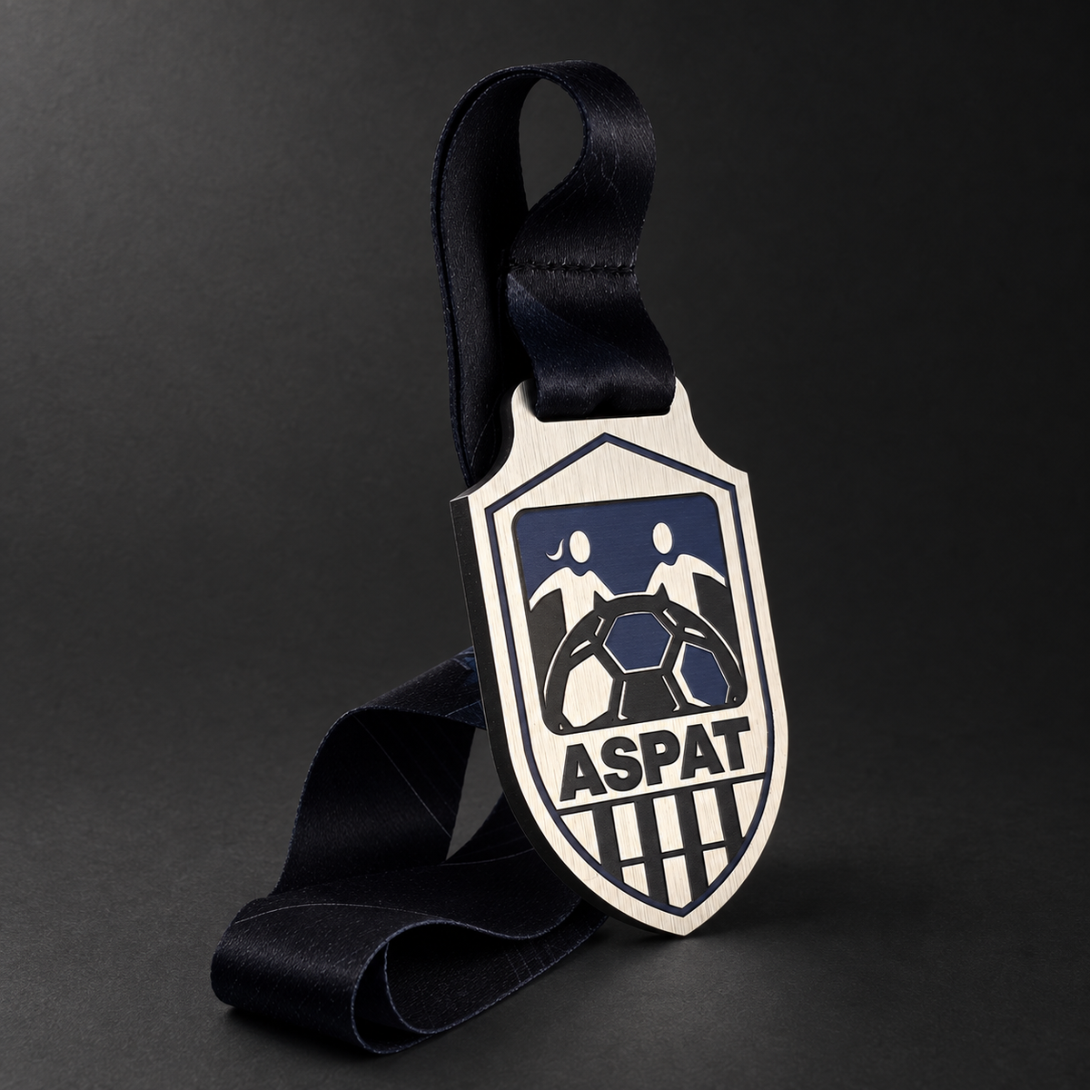 Médaille ASPAT en ACM ¼ po, forme d’écusson et ruban noir, sur fond graphite.